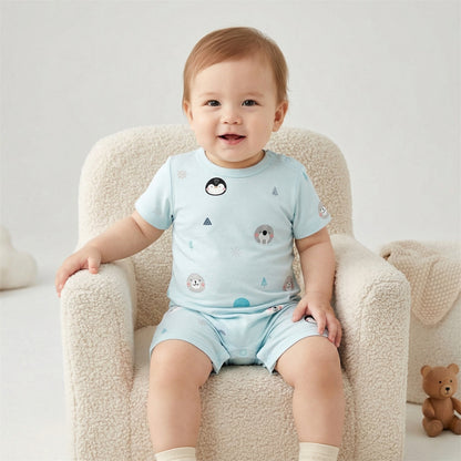 A happy 1-year-old baby wearing the Frosty Fam bamboo romper, sitting on a cozy cream-colored toddler chair in a bright studio setting