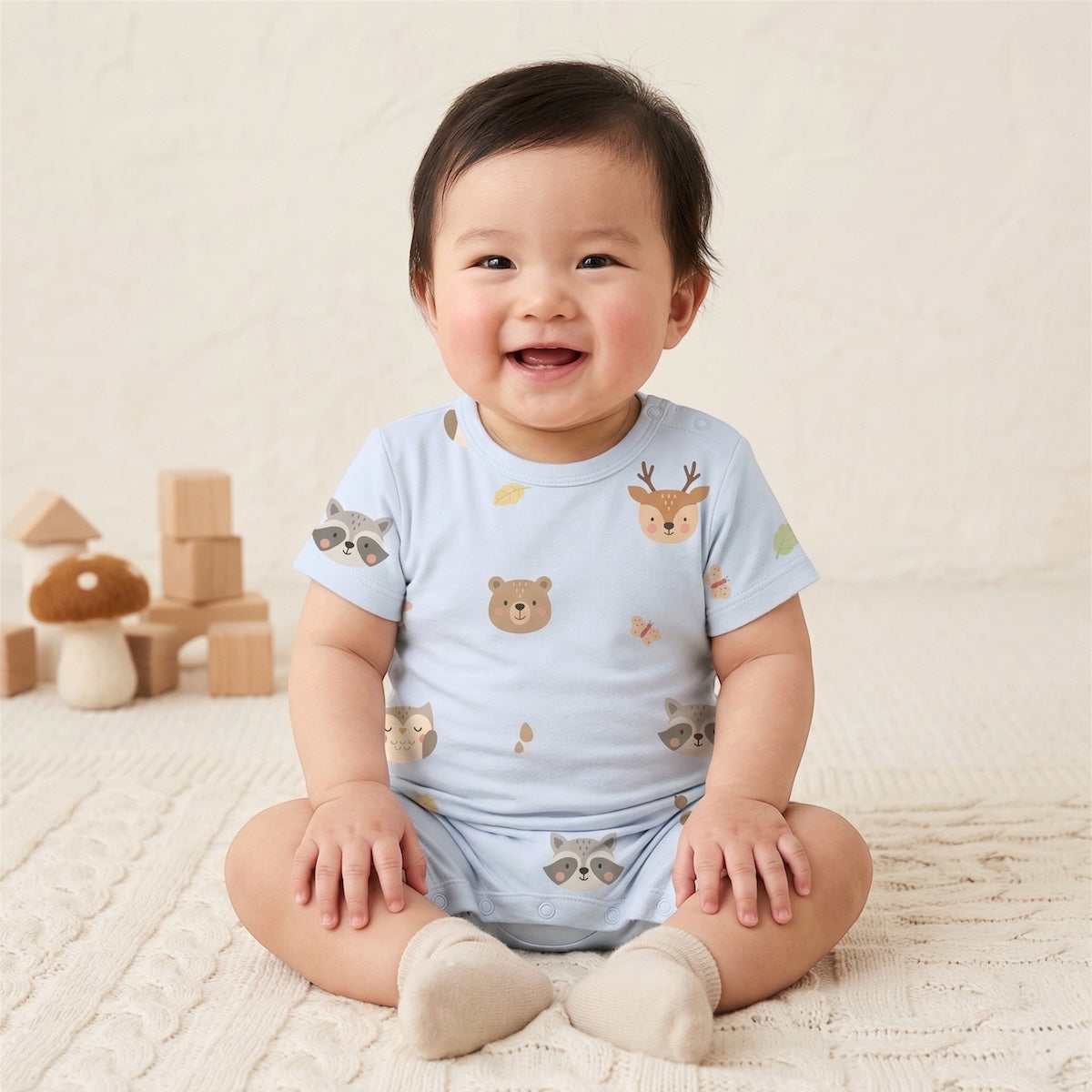 baby wearing cuteboid bamboo short rompers in woods fam blue design. whimsical woodland animal prints on it