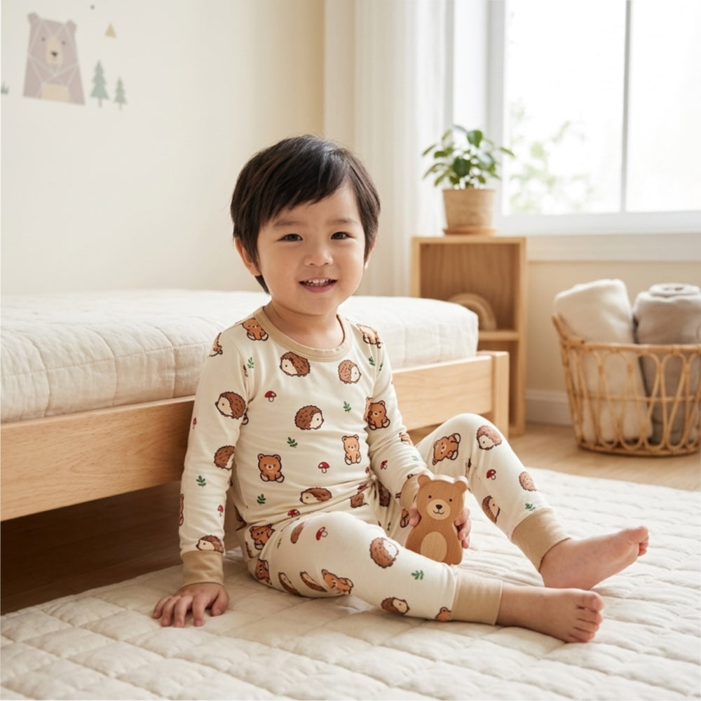 kids sitting at the bedside wearing cuteboid bamboo 2 piece sleepwear set slim fit design. Sleepwear design features hedgehog, teddy bear, and mushroom.