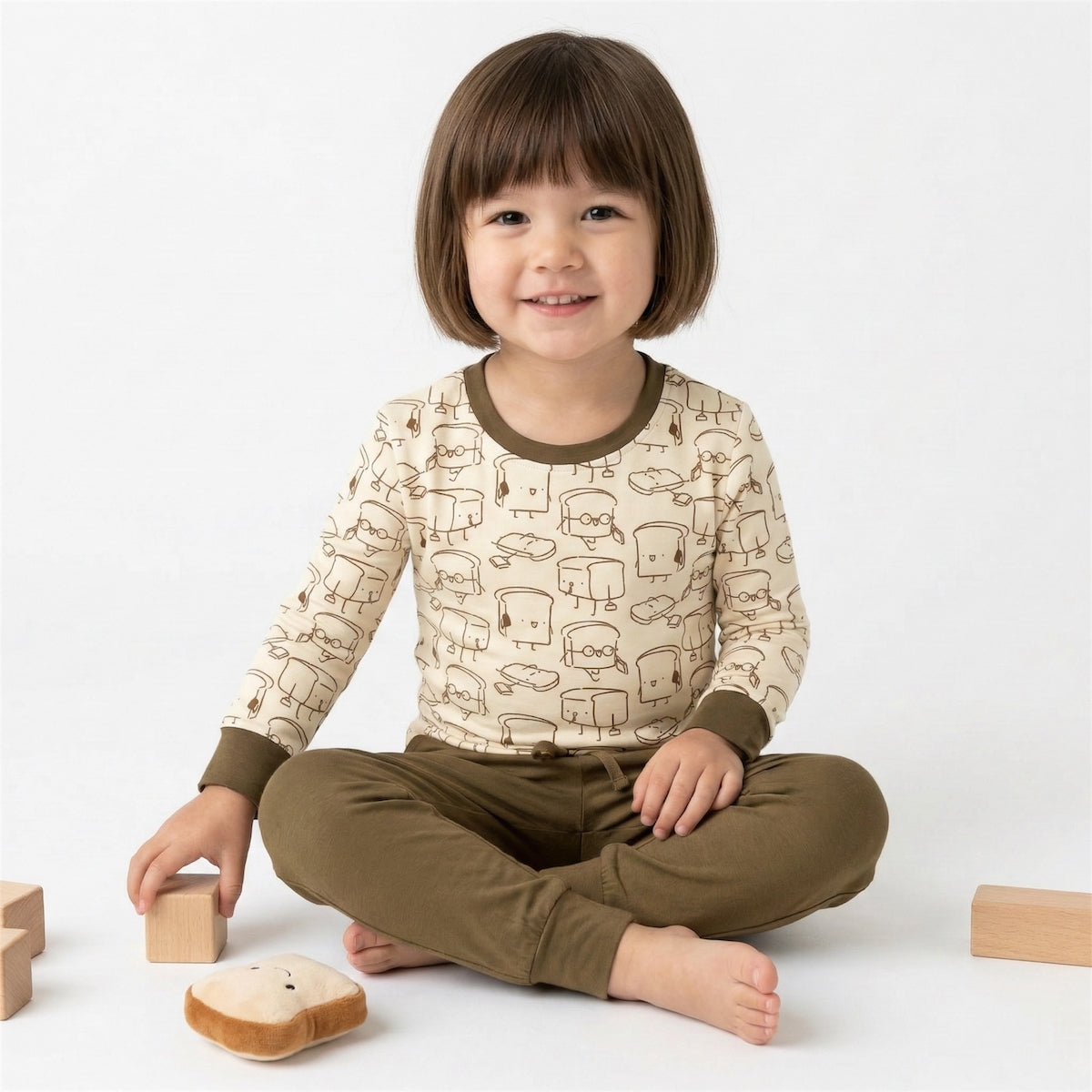 kids sitting on the floor wearing bamboo long sleeve sleepwear with cartoon bread prints on it. bamboo material sleepwear cuteboid brand