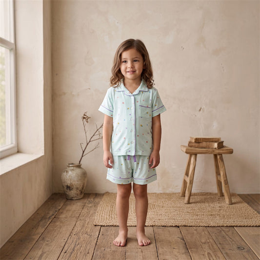 a young girl kids wearing cuteboid bamboo cooling pyjamas standing at the side of the window. The bamboo pyjamas is short sleeve and short pants version with coral, seashell and starfish designs on it